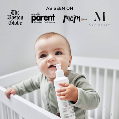 Baby holding a bottle in front of a crib with various media outlet logos above.