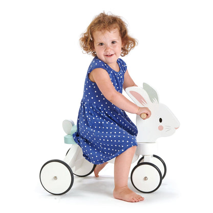 Child in a blue dress riding Tender Leaf Running Rabbit Ride On