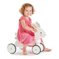 Child in a pink dress sitting on Tender Leaf Running Rabbit Ride On