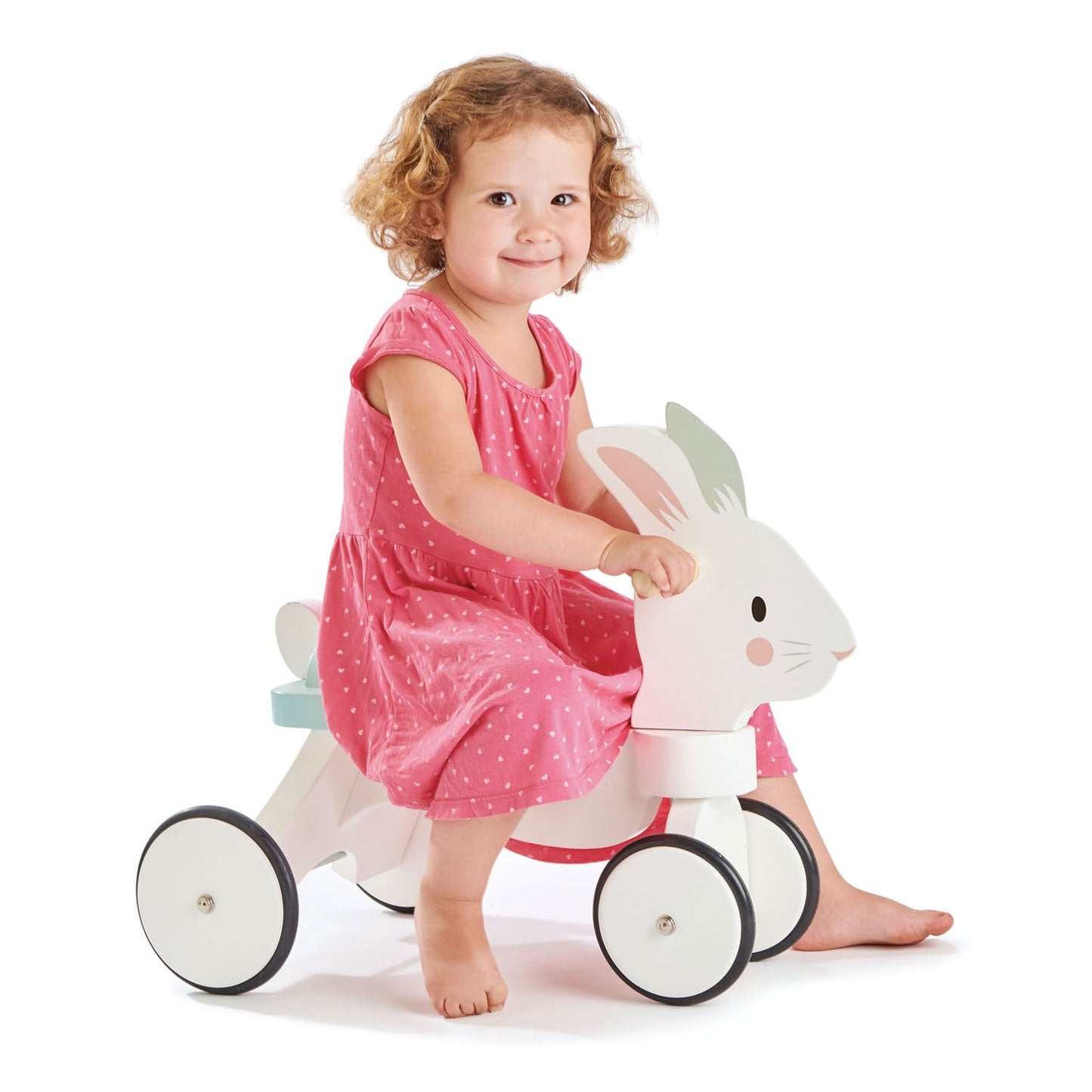 Child in a pink dress sitting on Tender Leaf Running Rabbit Ride On
