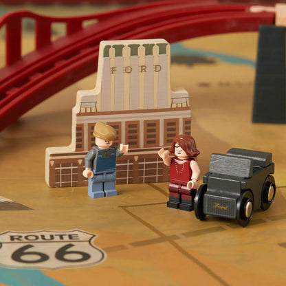 Toy figures and car on a toy map with a toy building in the background