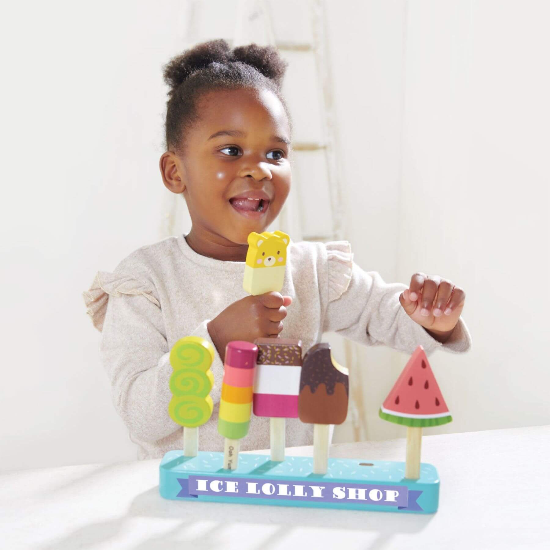 Child playing with a toy ice lolly shop set on a white background