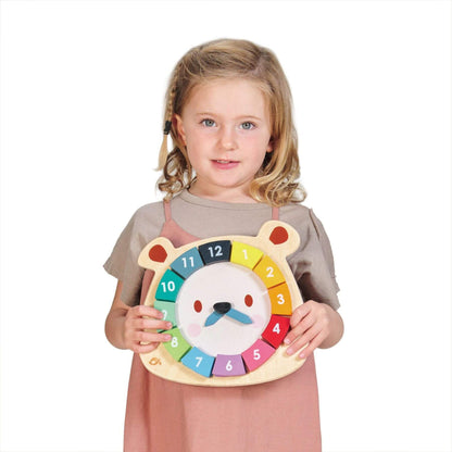 Child holding a colorful clock with a bear design on a white background