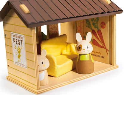 Toy rabbit and mouse inside a wooden house with a yellow couch and carrot design on the wall.