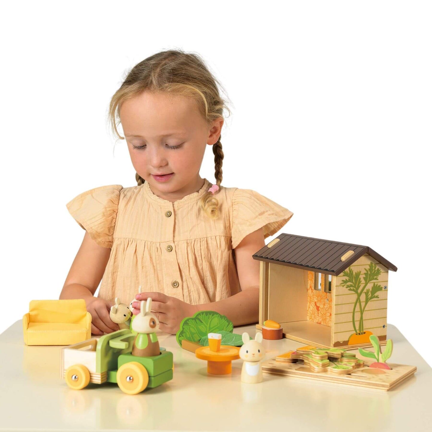 Young girl playing with Tender Leaf Bunny's Carrot Patch on a white surface