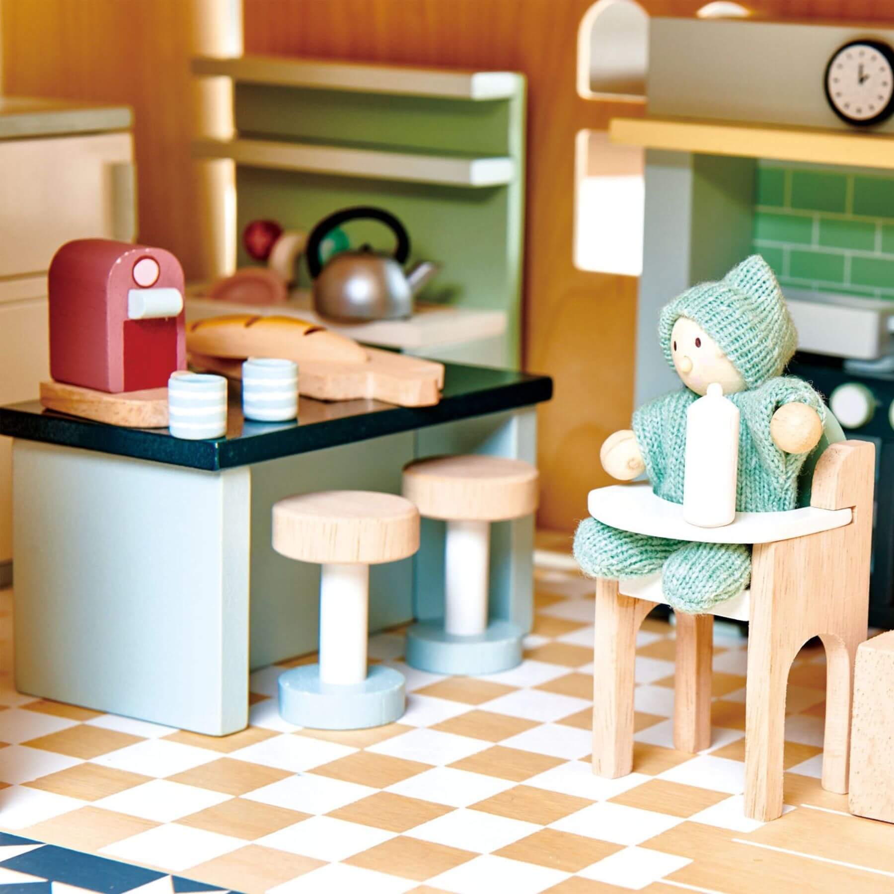 Toy kitchen set with a child's figurine, stools, and kitchen items on a checkered floor.