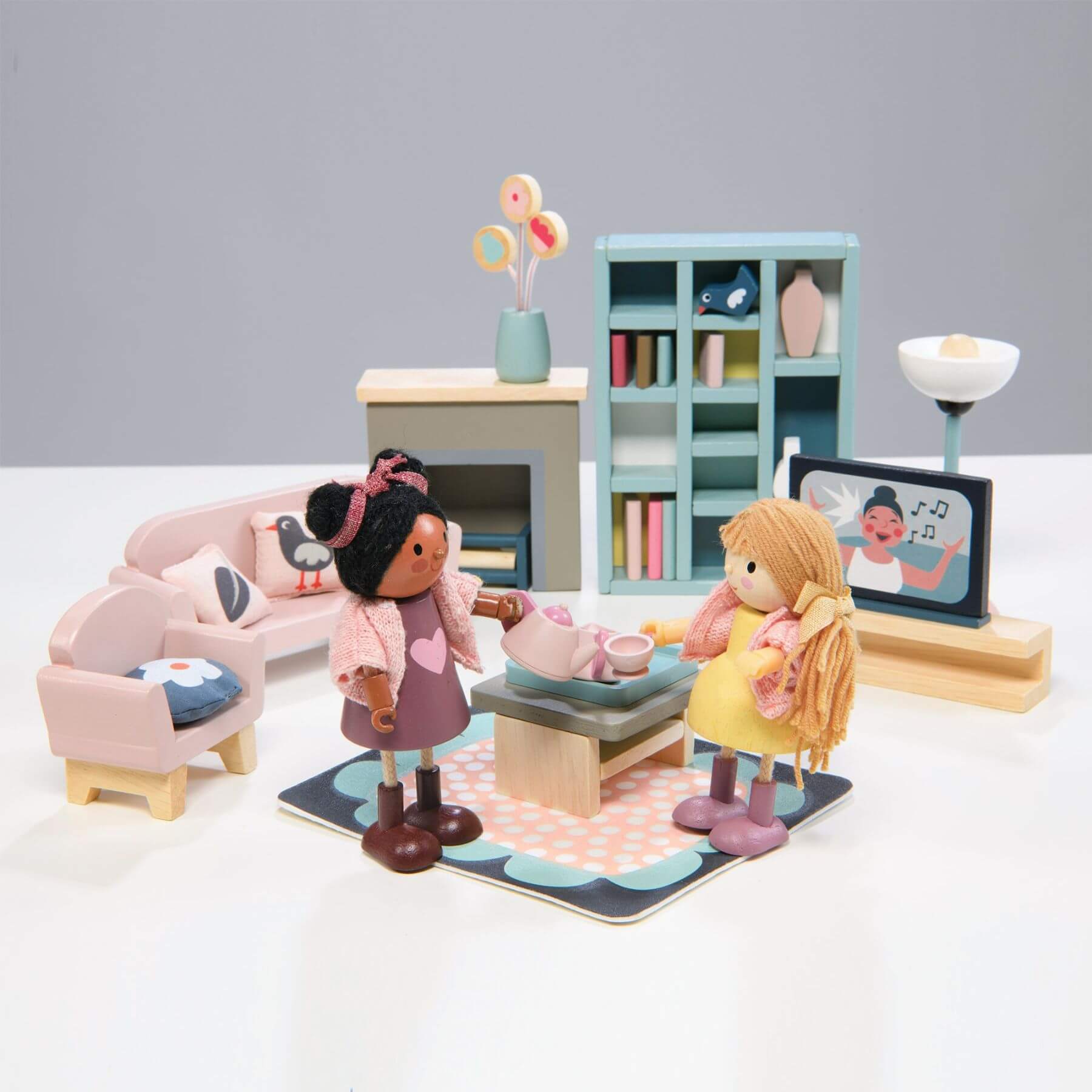 Toy living room set with dolls and furniture on a white surface.