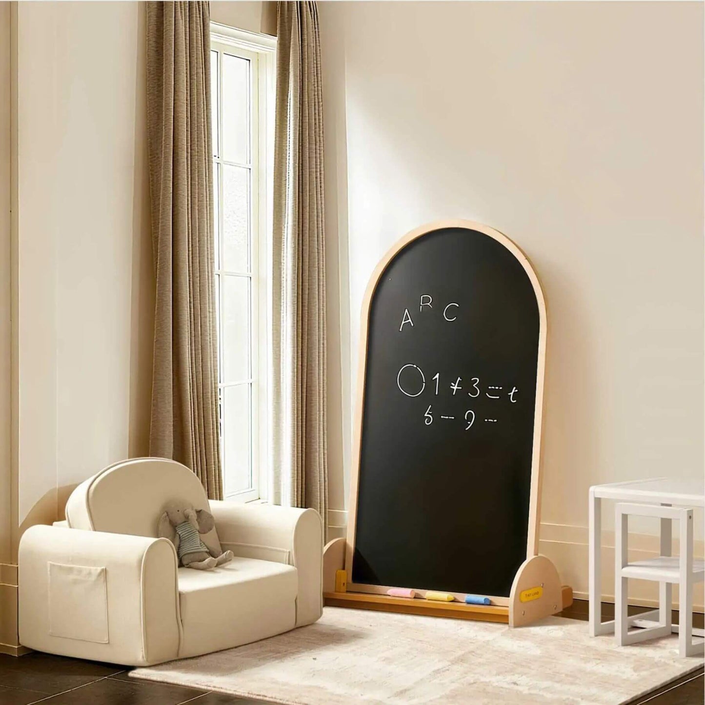 Children's room with a beige chair and a large blackboard on a wall.