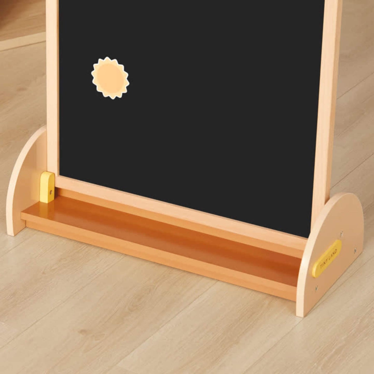 Wooden children's easel with blackboard and chalk holder on a wooden floor