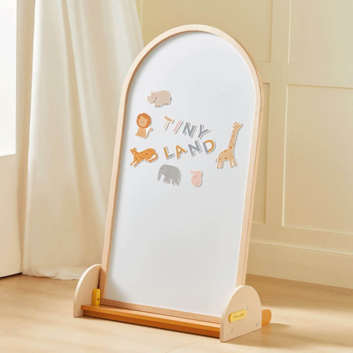 Wooden mirror with 'Tiny Land' and animal illustrations on a light wooden floor.