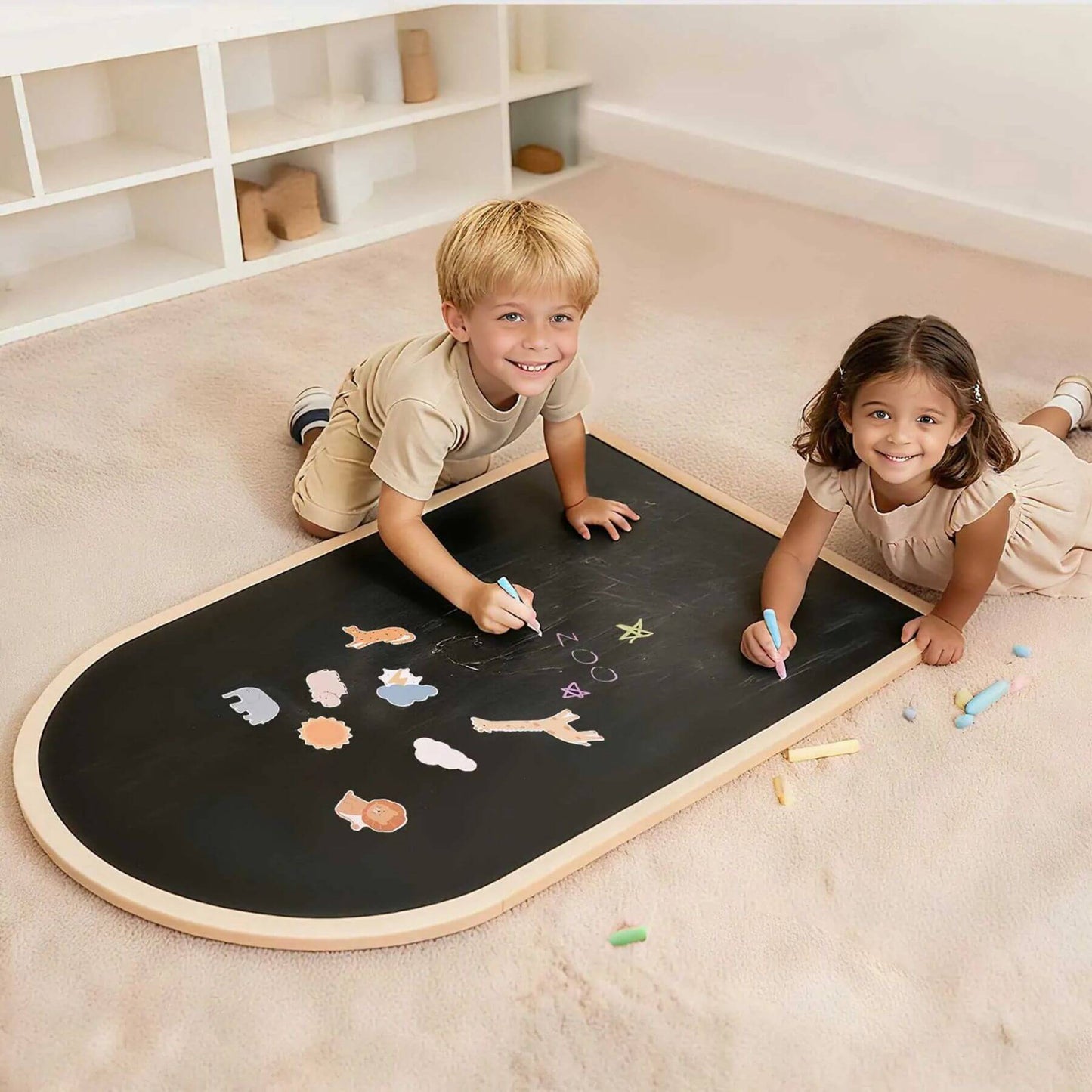 Two children playing with a large blackboard on the floor.