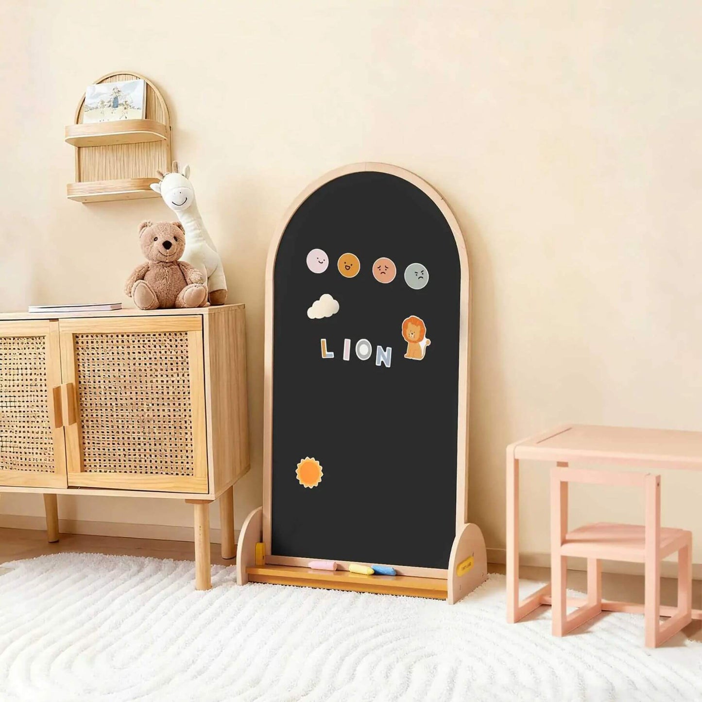 Children's blackboard with wooden frame in a room with a teddy bear and small table.