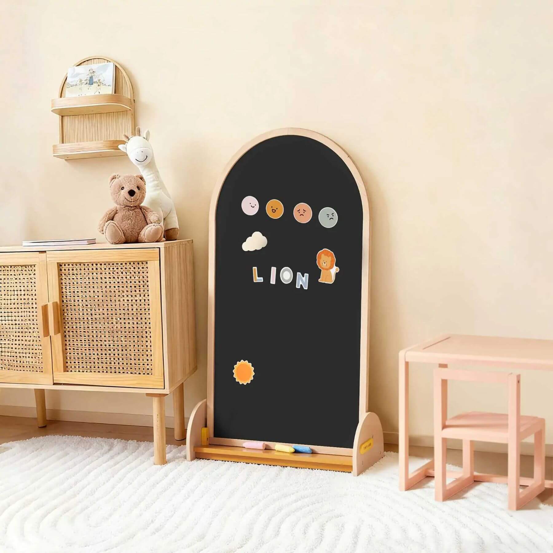 Children's blackboard with wooden frame in a room with a teddy bear and small table.