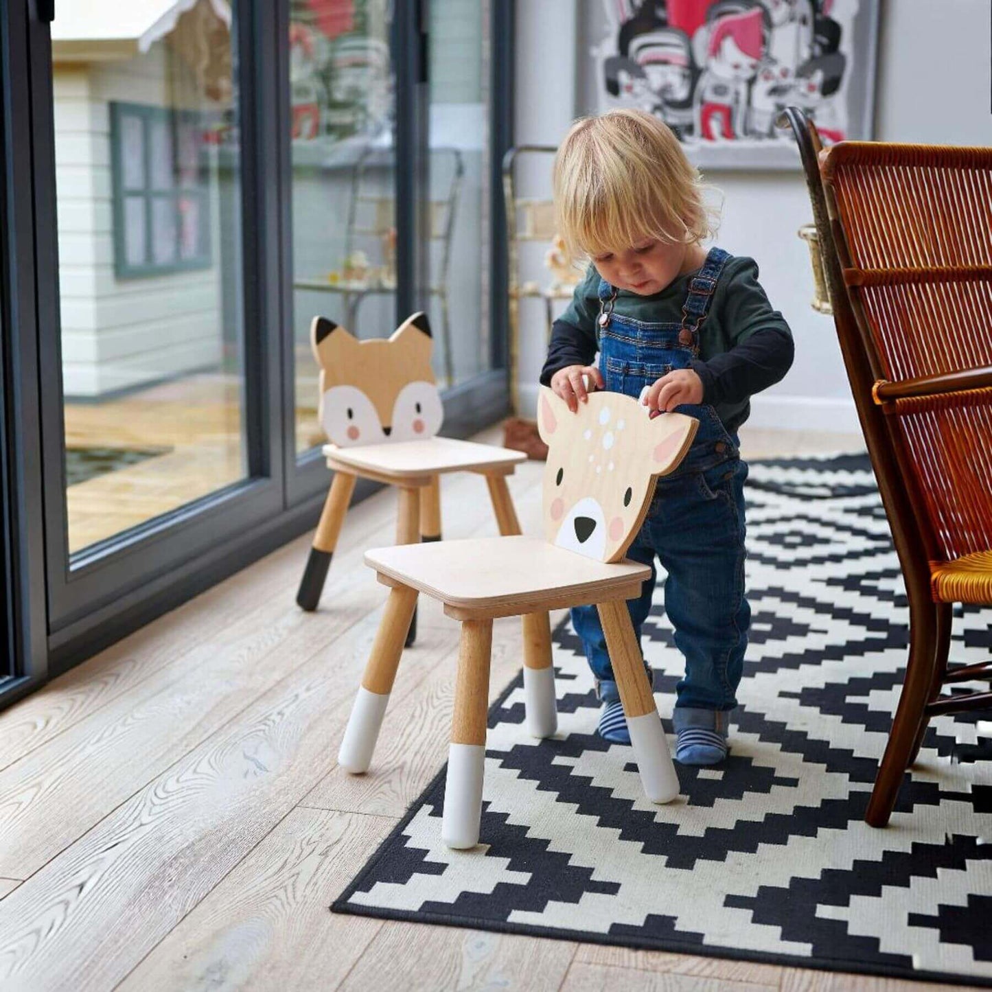 Child playing with Tender Leaf Forest Deer Chair in a room with a glass door and rug.