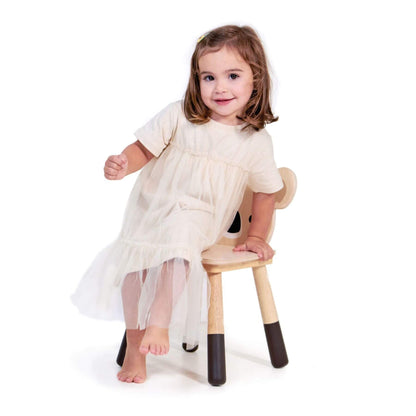 Young girl sitting on Tender Leaf Forest Koala Chair wearing a white dress with sheer overlay.