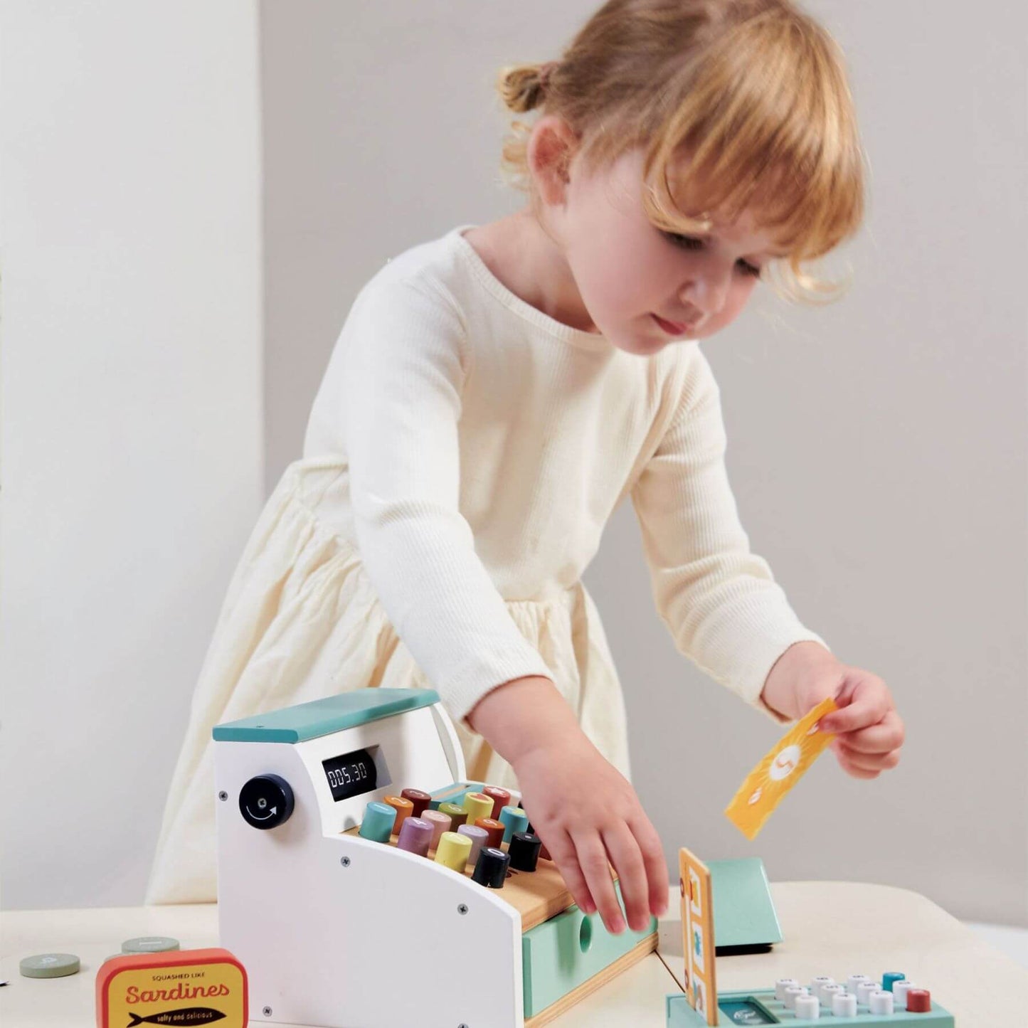Child playing with Tender Leaf General Stores Till on a light-colored surface.