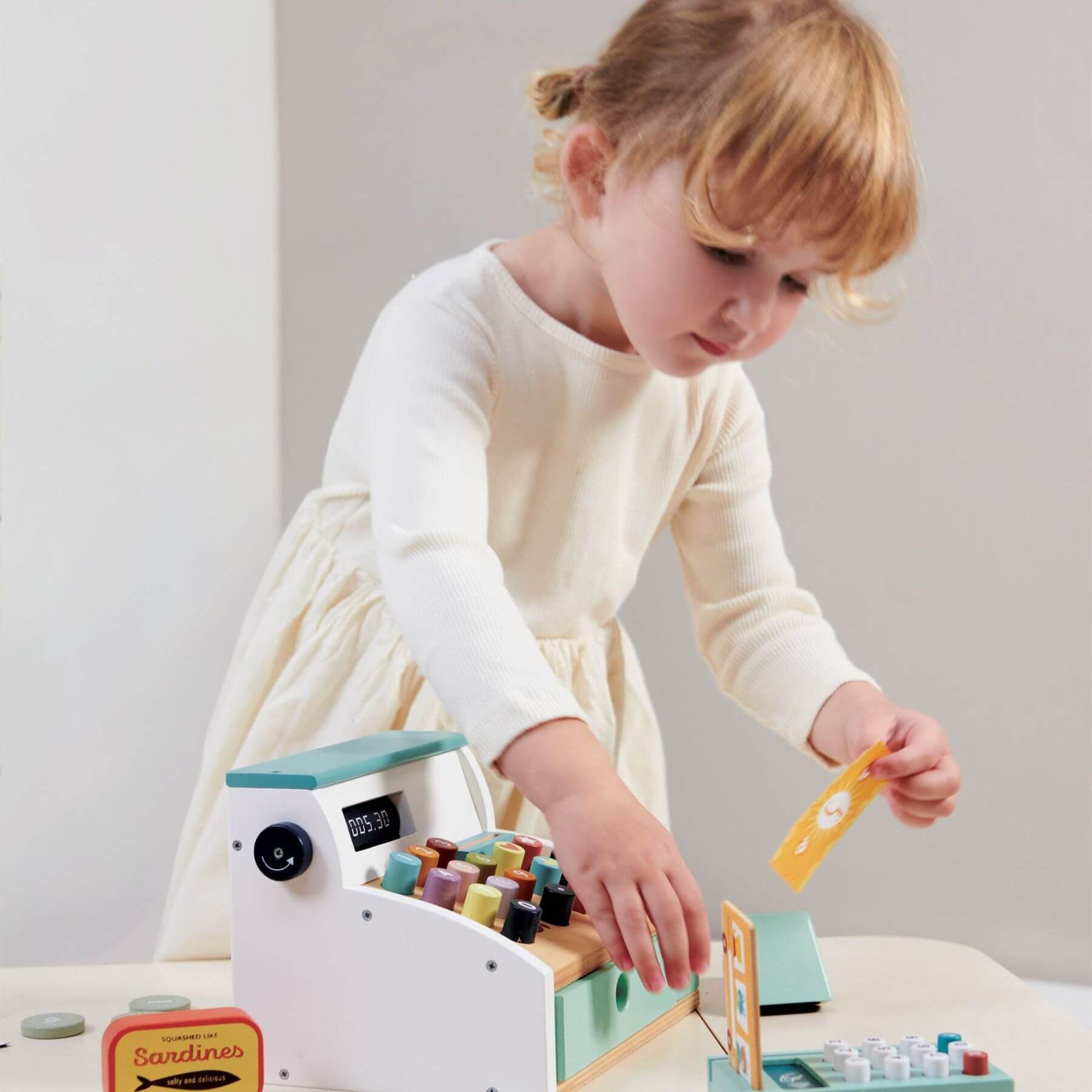 Child playing with Tender Leaf General Stores Till on a light-colored surface.