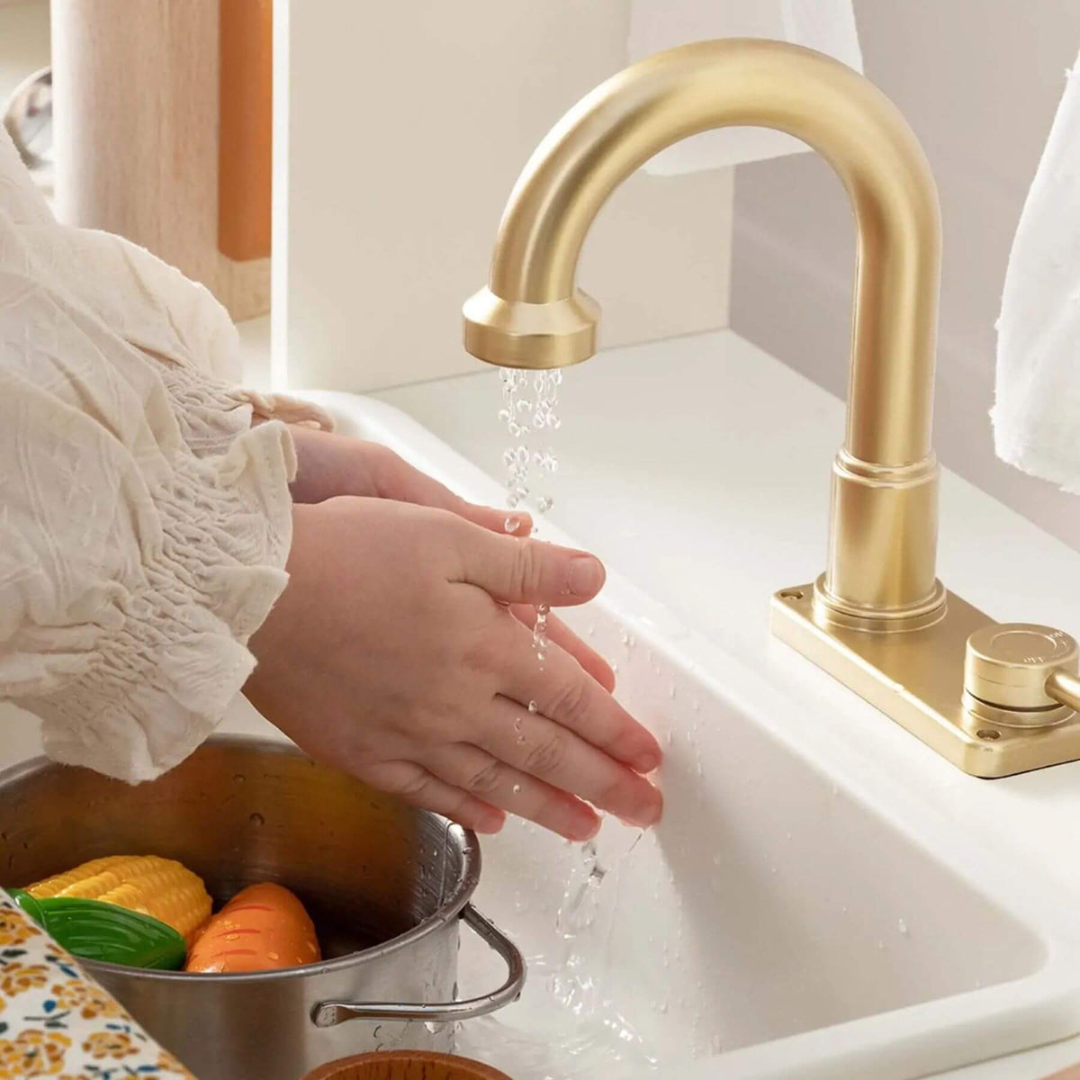 Person washing vegetables in a sink with a gold faucet.