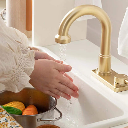 Person washing vegetables in a sink with a gold faucet.