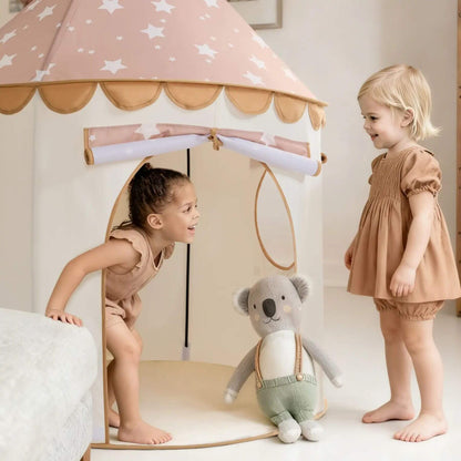 Two young girls playing with Tiny Land® Kids Tent - Brown and a stuffed koala toy in a room.