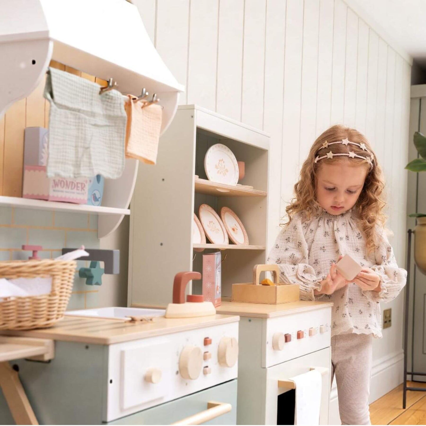 Child playing with a toy kitchen set in a bright room