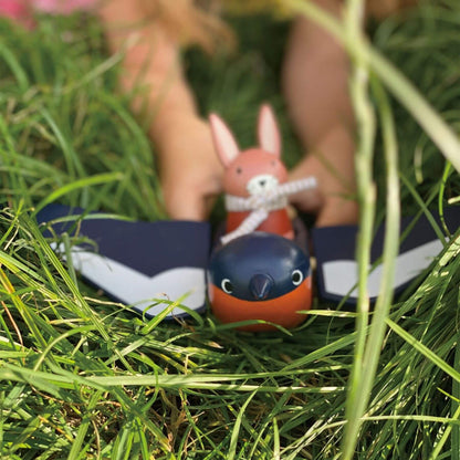 A small bird-shaped toy with a rabbit figure on top, resting on green grass outdoors.