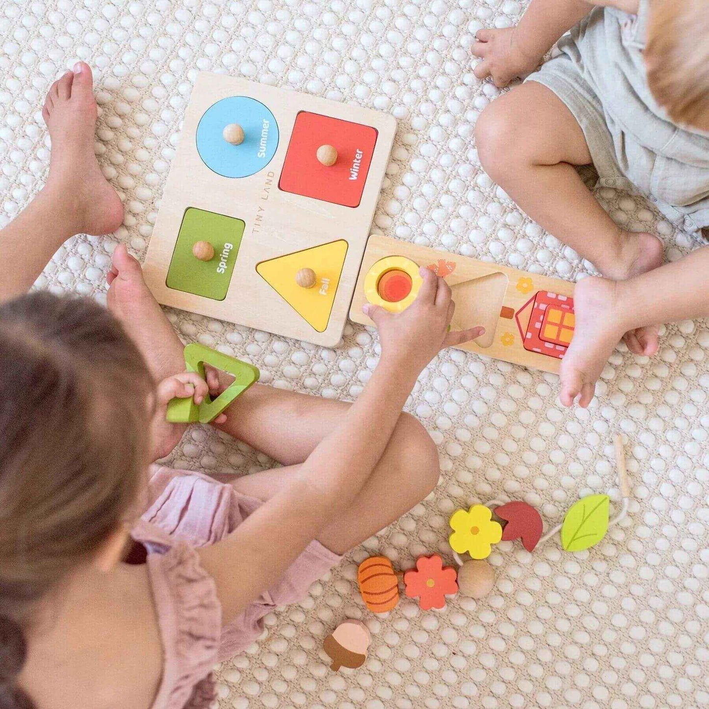 Children playing with wooden shape sorting toys on a textured floor.