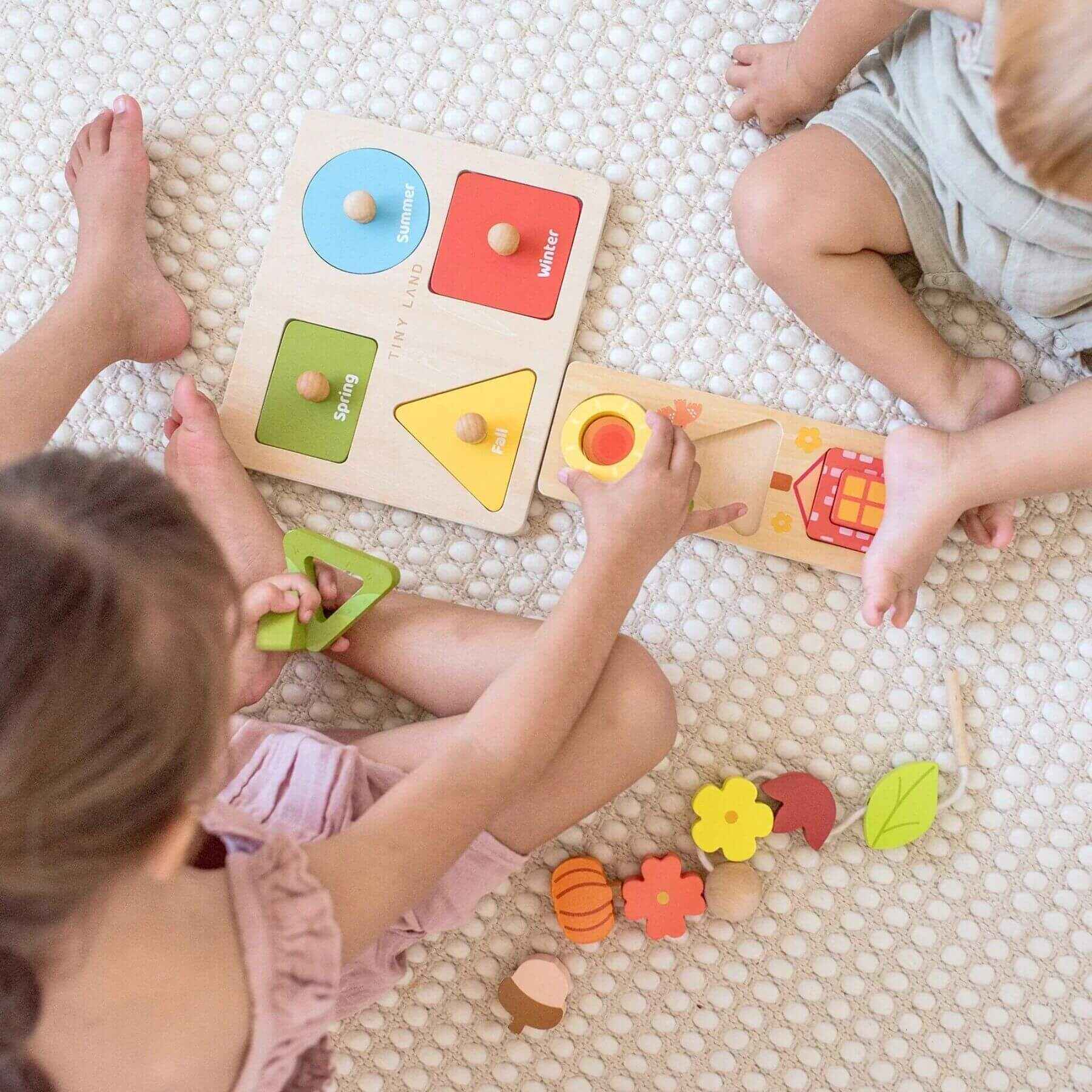 Children playing with wooden shape sorting toys on a textured floor.