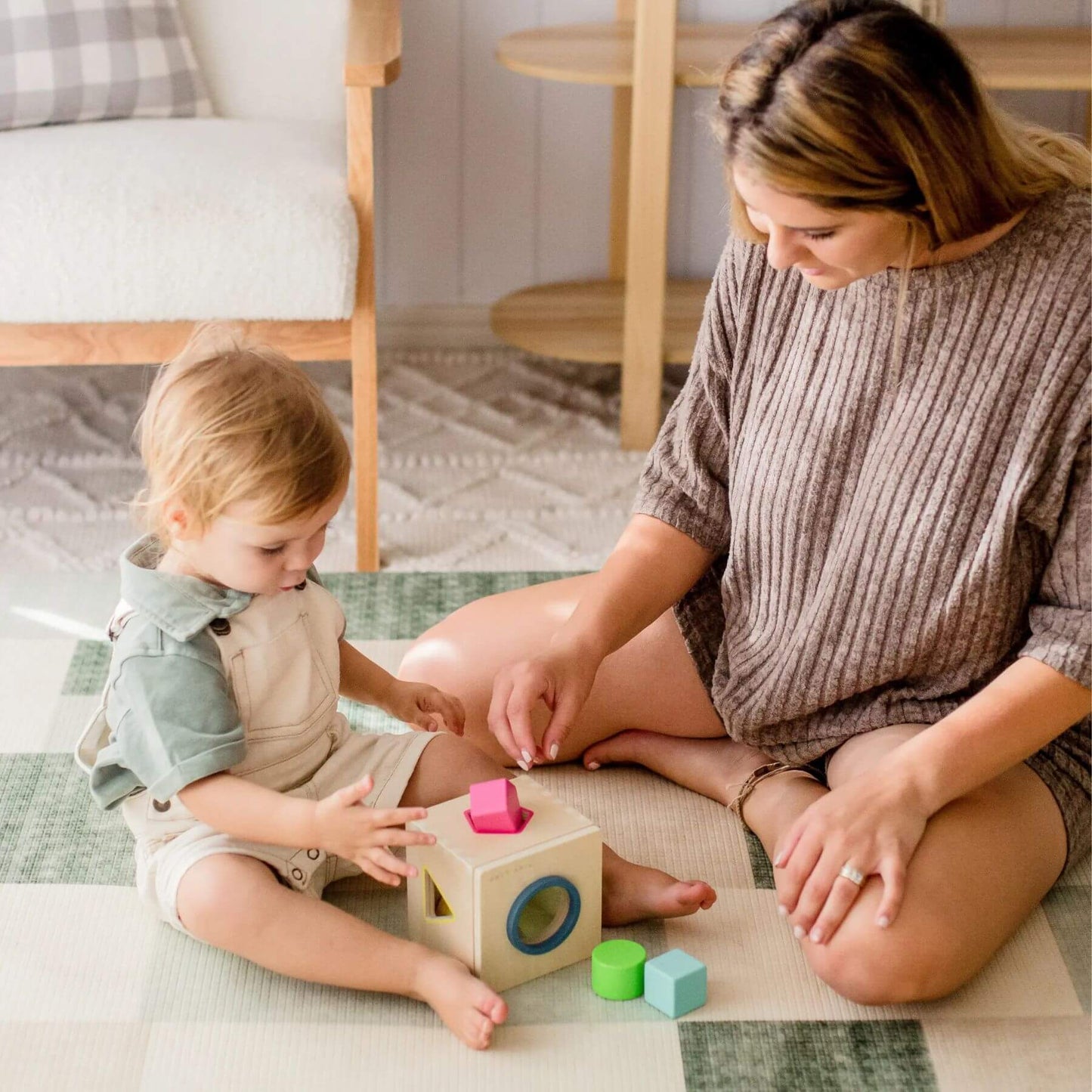 Woman and child playing with colorful blocks on a rug