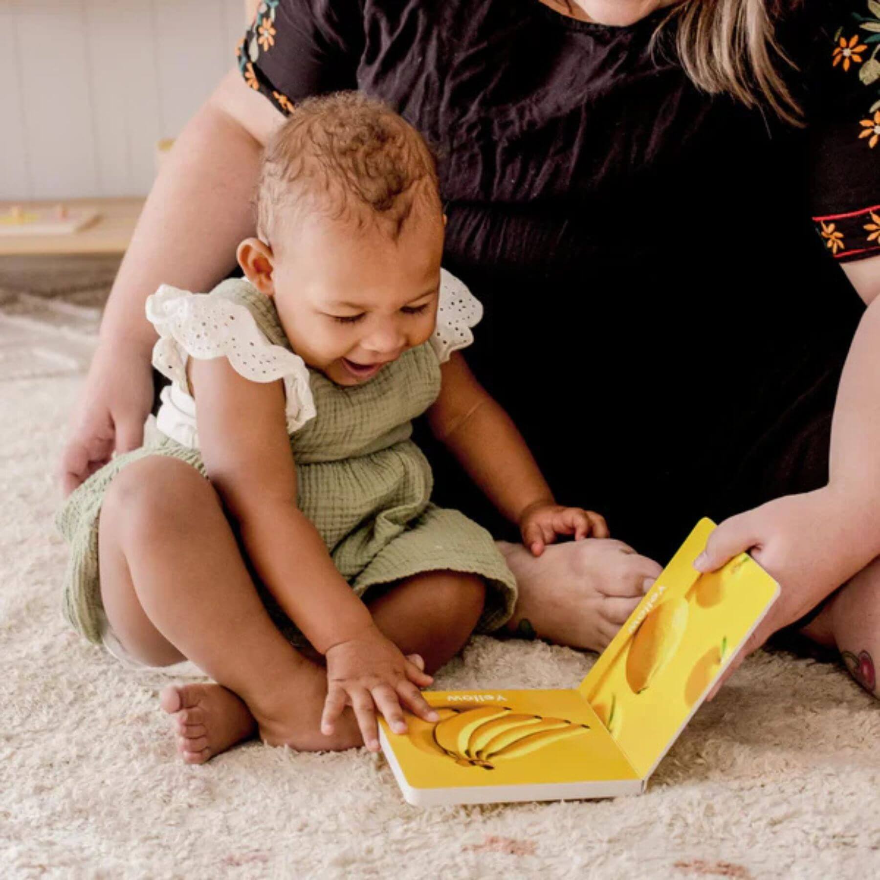 Woman reading a book to a baby on the floor