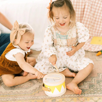 Two young children playing with a toy on a patterned rug.