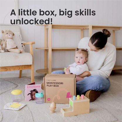 Woman holding a baby with Montessori play items and a box labeled 'Montessori Play Box' in a home setting.