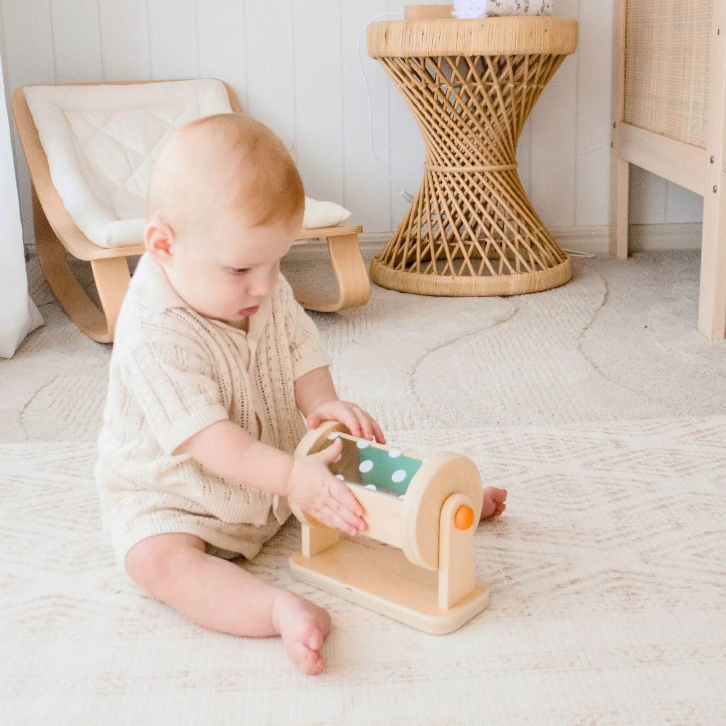 Child playing with a wooden toy on a light-colored floor.
