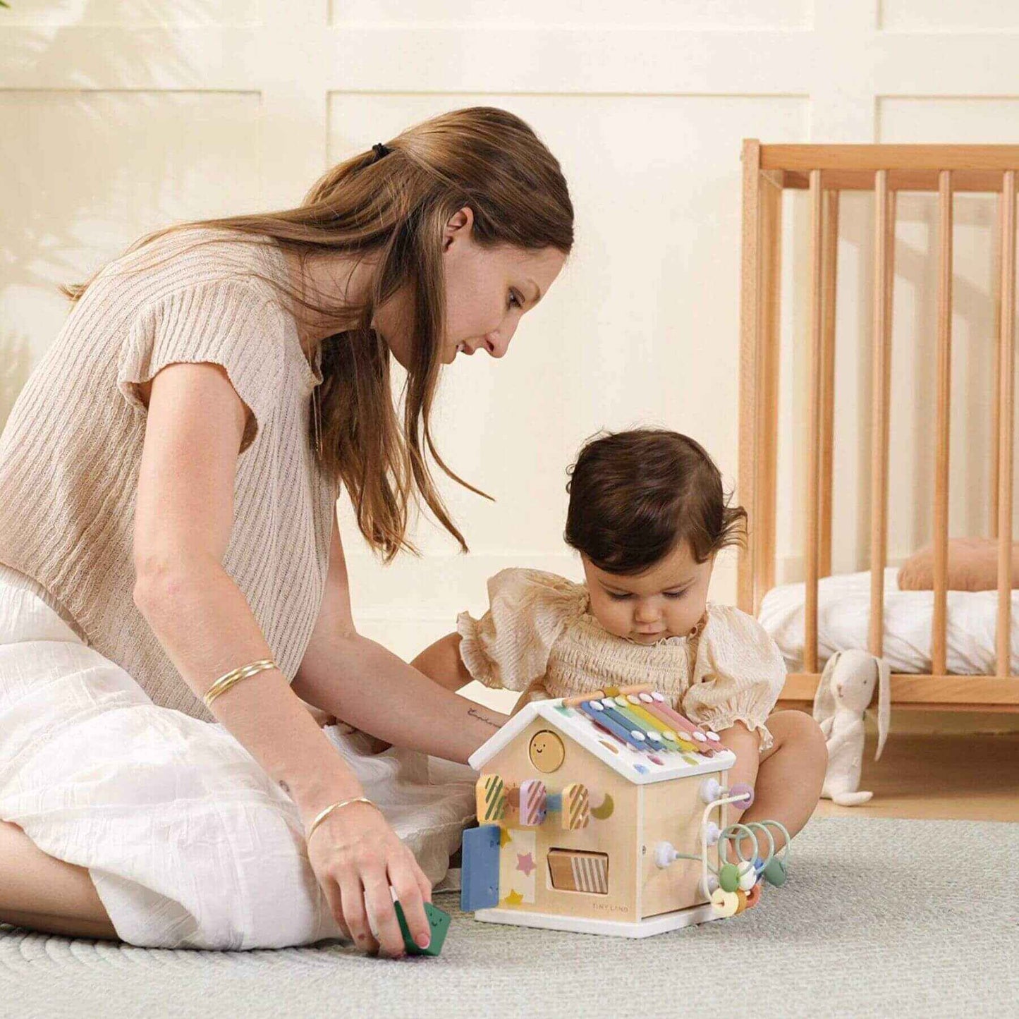 Woman and child playing with Tiny Land® Cottage Activity Cube - Morandi in a nursery.