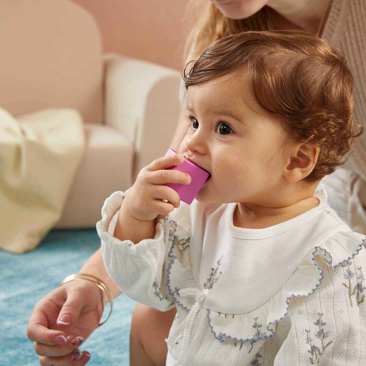 Baby holding a pink object with a blurred background