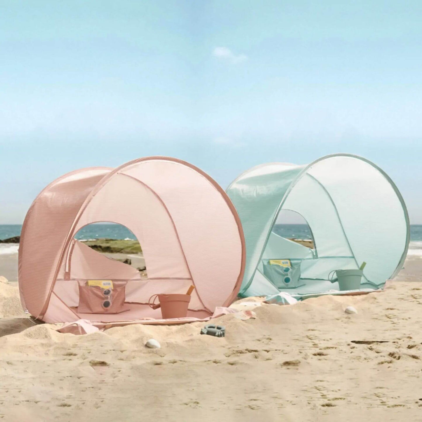 Pink and clear beach tents on a sandy beach with ocean view