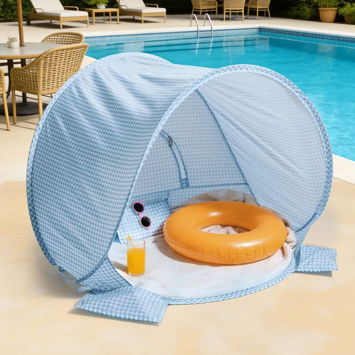 Blue pop-up canopy tent with an orange inflatable ring and a glass of juice by a pool.