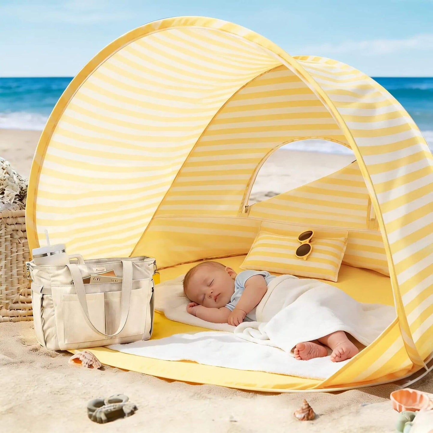 Yellow striped baby beach tent on a sandy beach with a baby inside