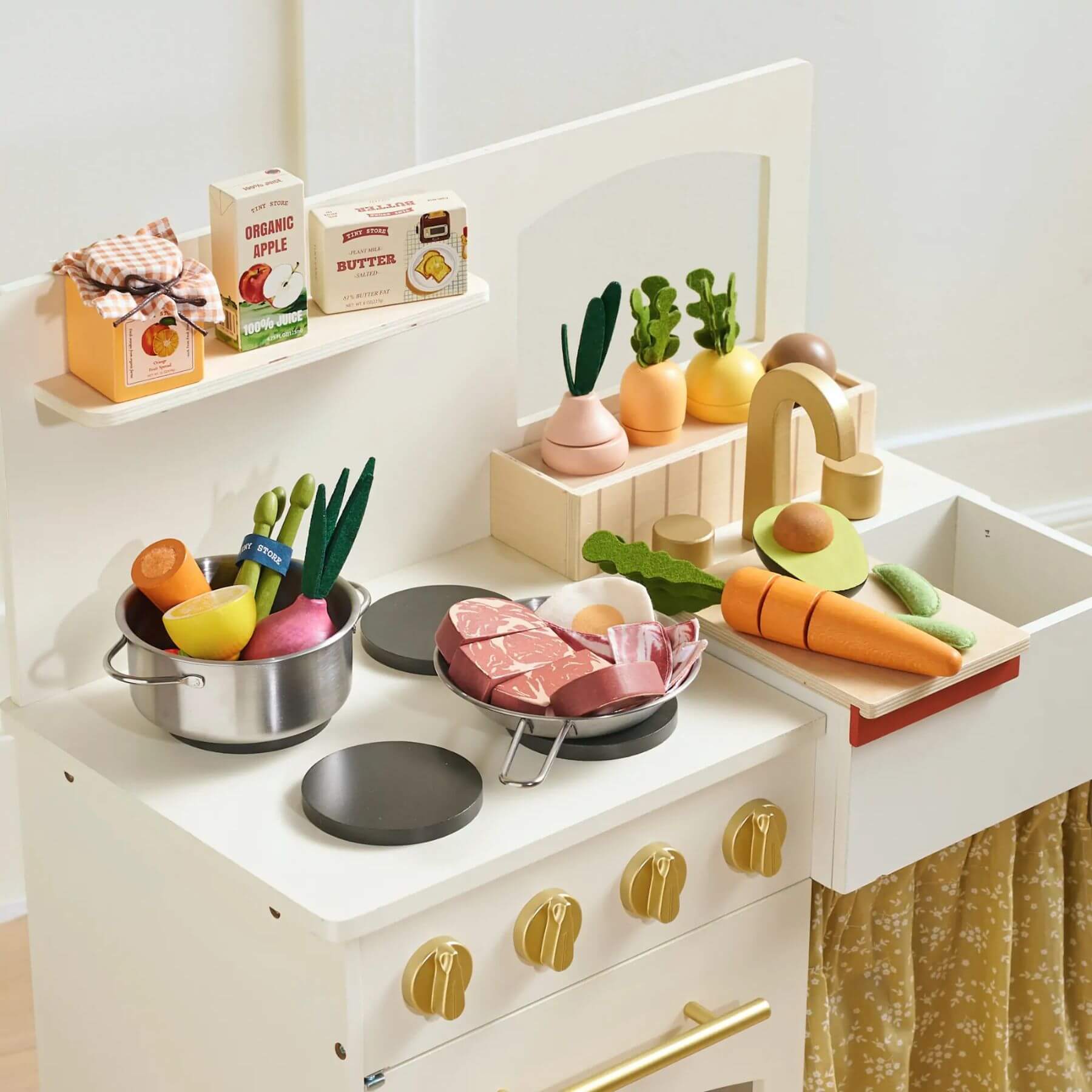 Children's play kitchen set with toy food and utensils on a white countertop.