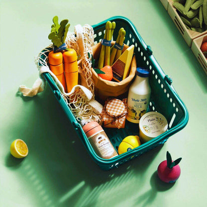 Toy grocery basket with toy food items on a green surface