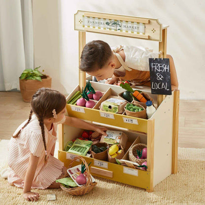 Children playing with a toy farmers market set in a room.