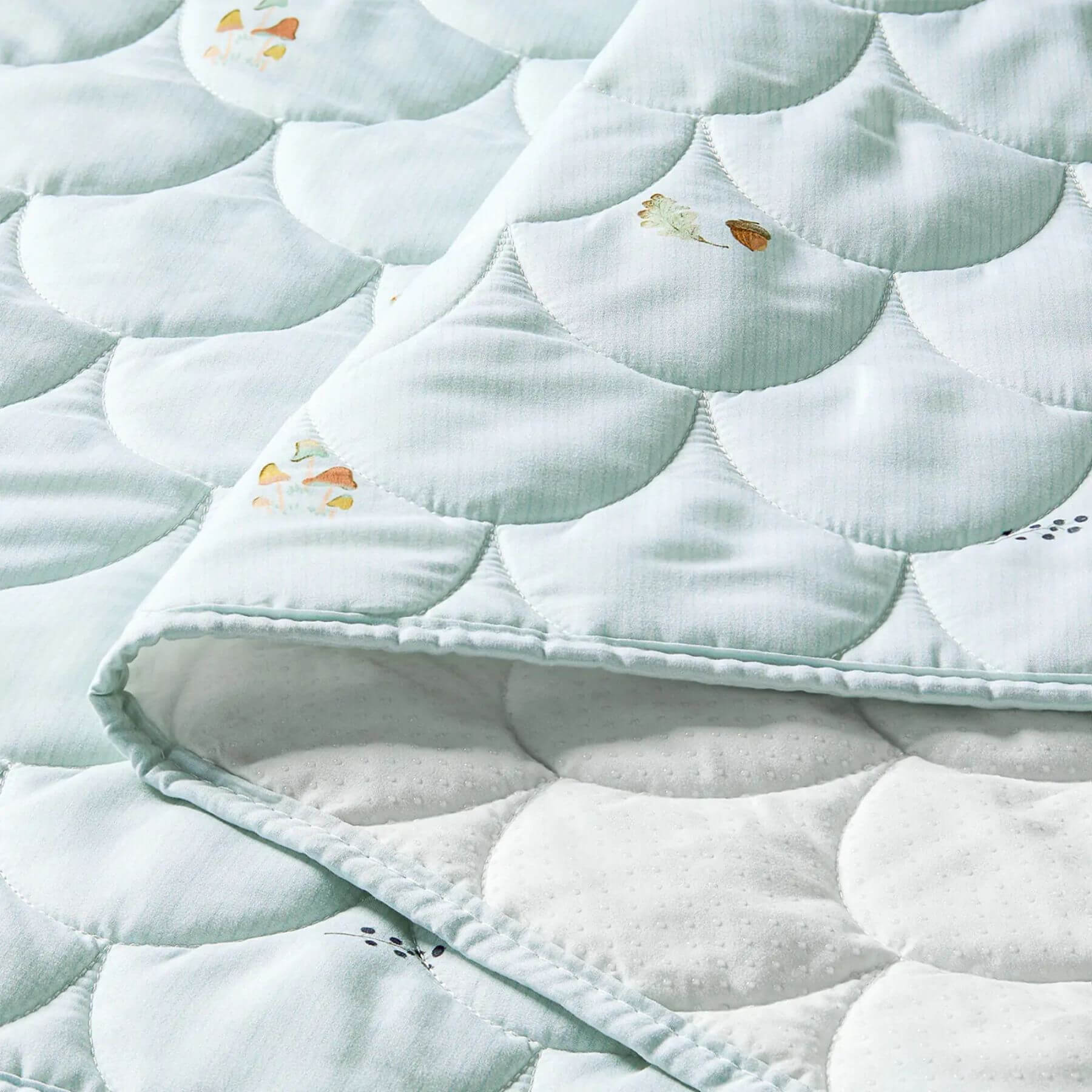 Close-up of a quilt with circular patterns and small decorative elements on a light blue background.