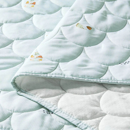 Close-up of a quilt with circular patterns and small decorative elements on a light blue background.