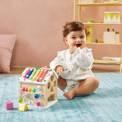 Baby playing with Tiny Land® Cottage Activity Cube - Rainbow on a blue rug.