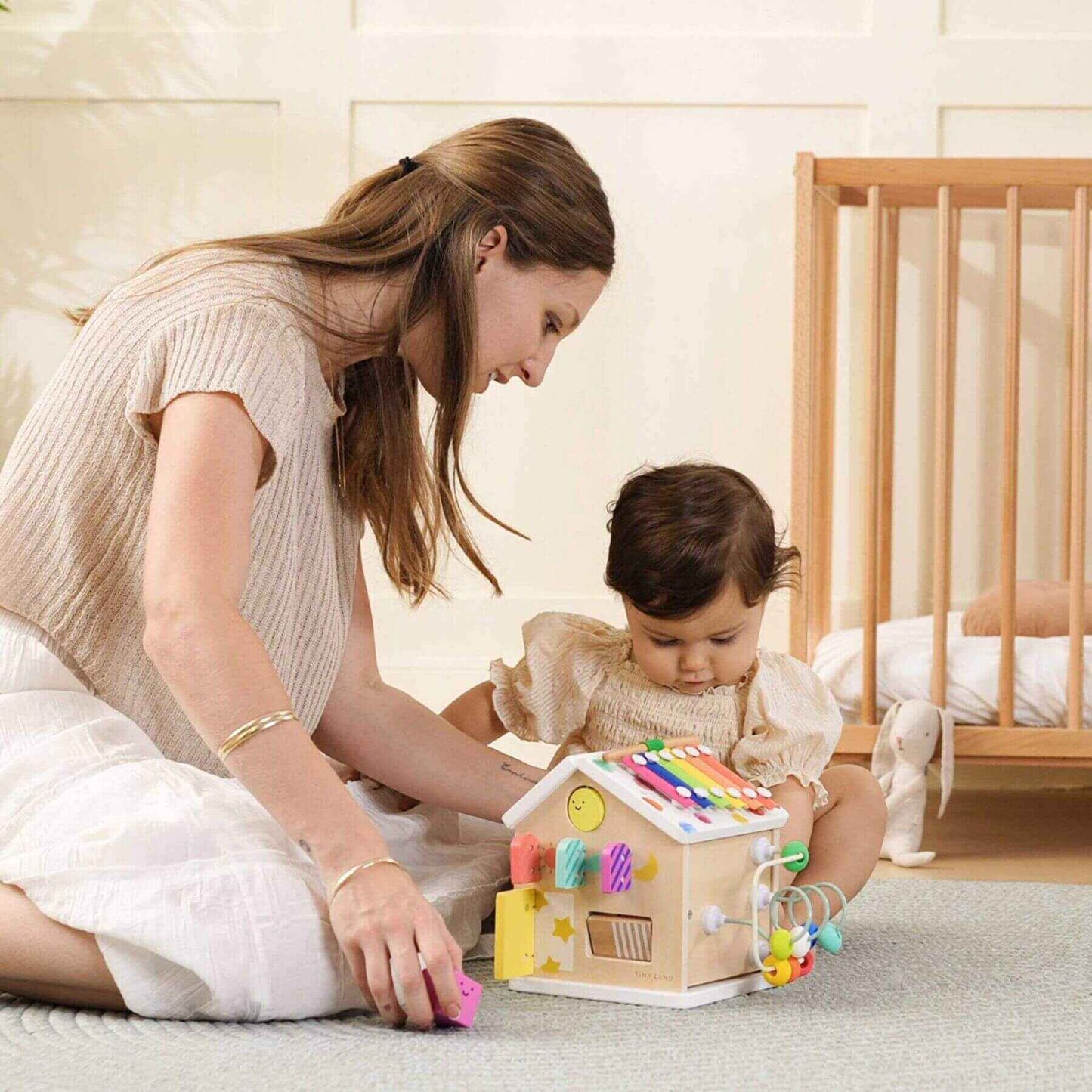 Woman and child playing with Tiny Land® Cottage Activity Cube - Rainbow in a nursery.