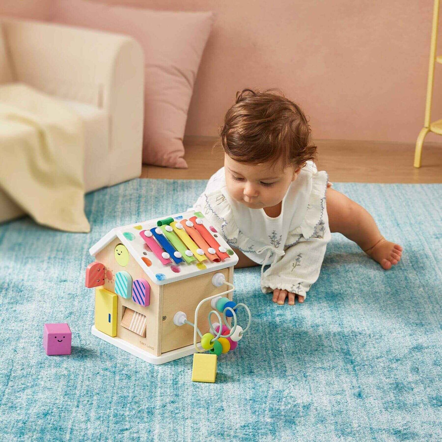 Baby playing with Tiny Land® Cottage Activity Cube - Rainbow on a blue carpet