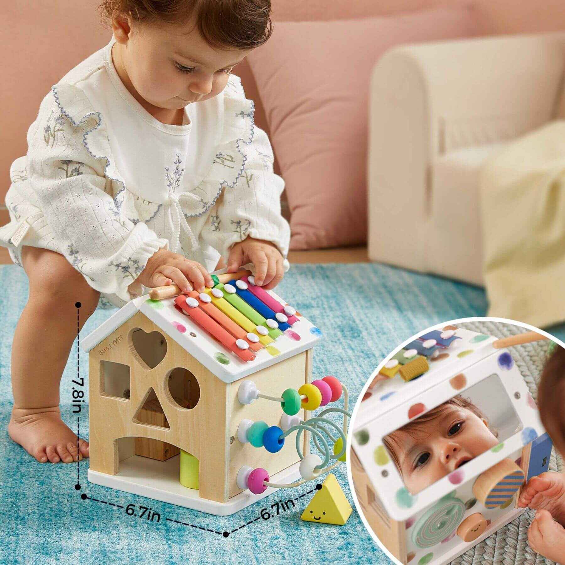 Child playing with Tiny Land® Cottage Activity Cube - Rainbow on a blue rug.