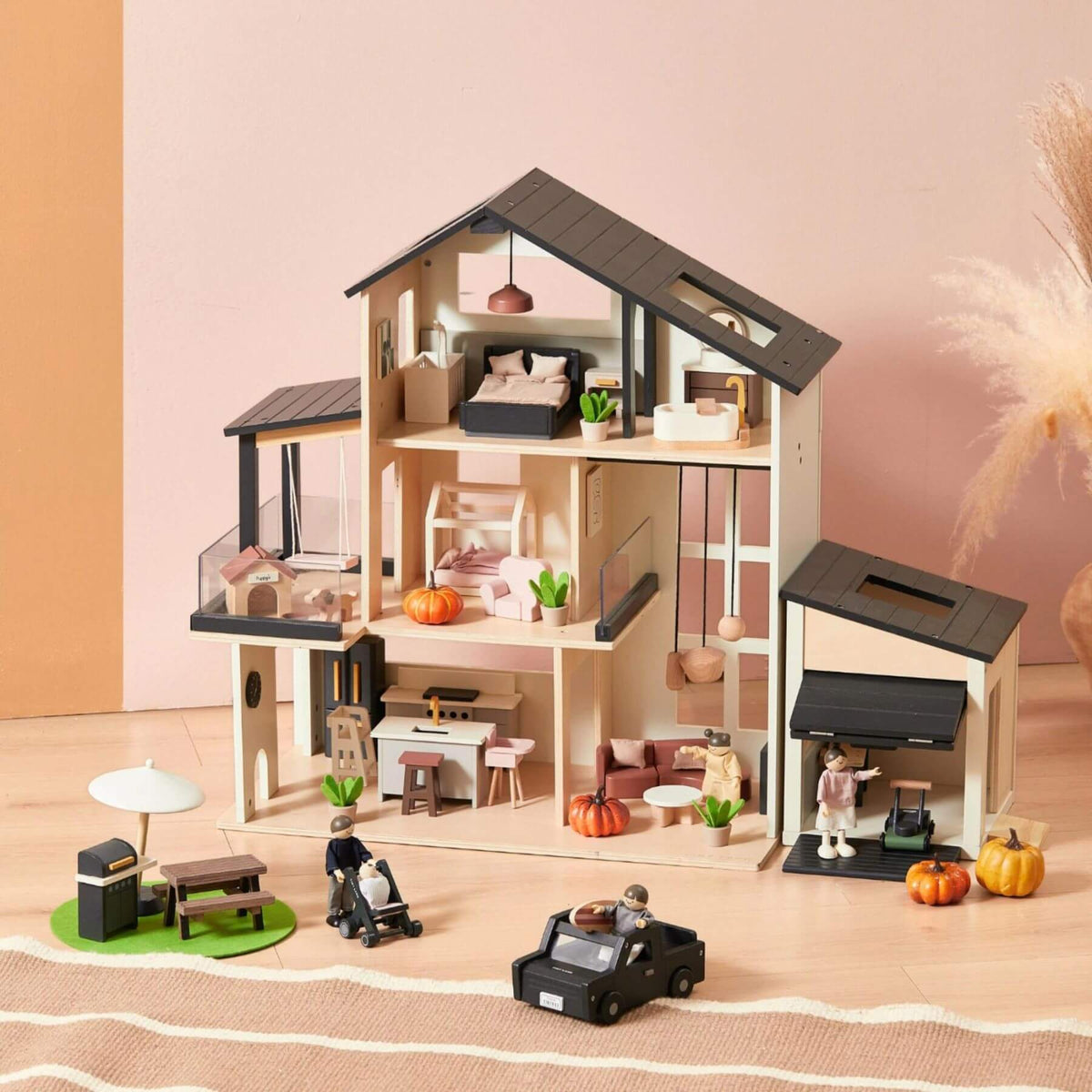 Tiny Land Sweet Family Gift Set: an open multi-story home, attached garage, small outdoor patio area, and tiny cars, furniture, plants, and figurines, arranged on a wooden surface against a soft beige and peach background.