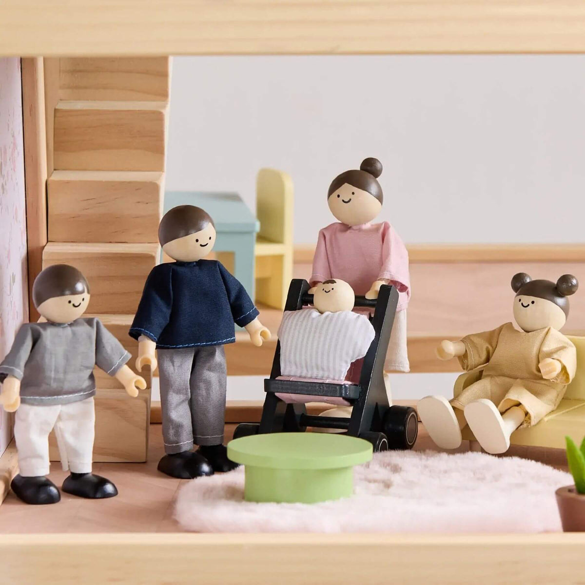 Wooden toy figures of a family in a living room setting with furniture and decor.