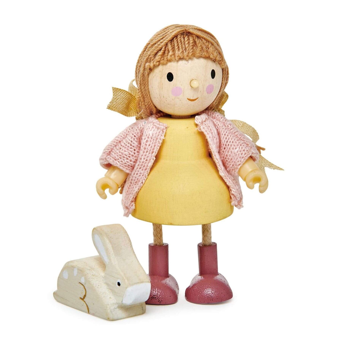 Toy doll with a yellow dress and pink sweater standing next to a wooden rabbit on a white background